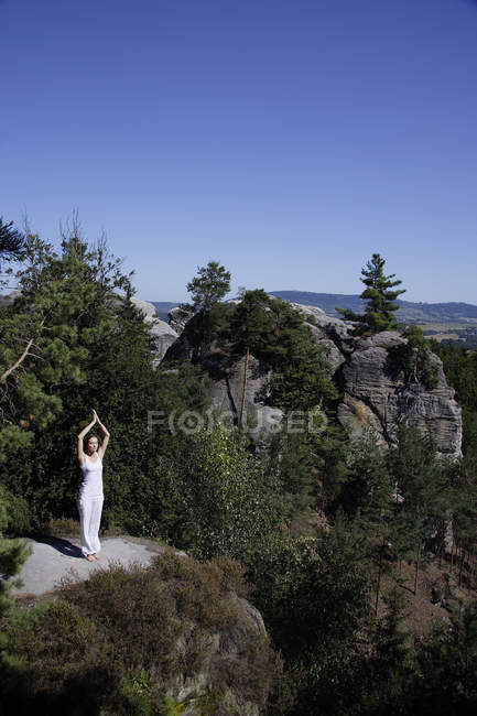 Woman doing yoga on top of mountain — Stock Photo