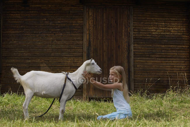 Menina sentada em frente à cabra — Fotografia de Stock