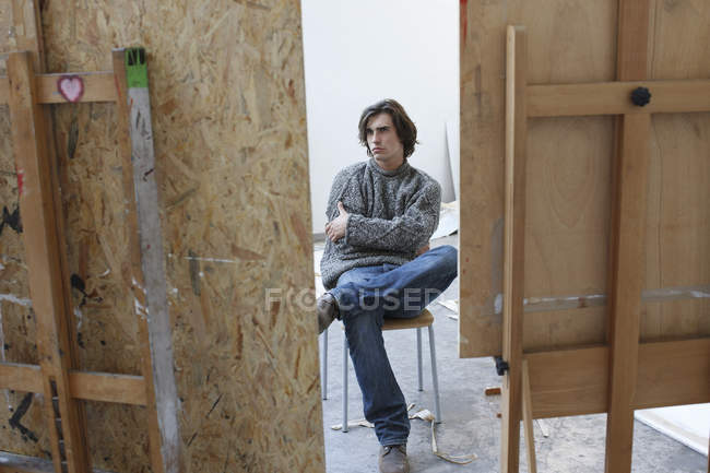 Молодой человек сидит в художественной студии — стоковое фото
