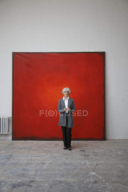 Жінка стоїть в художній студії на червоному тлі — стокове фото