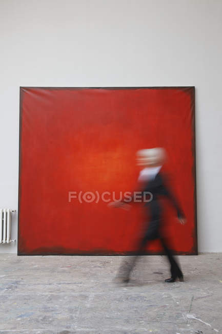 Woman walking by red painting — Stock Photo