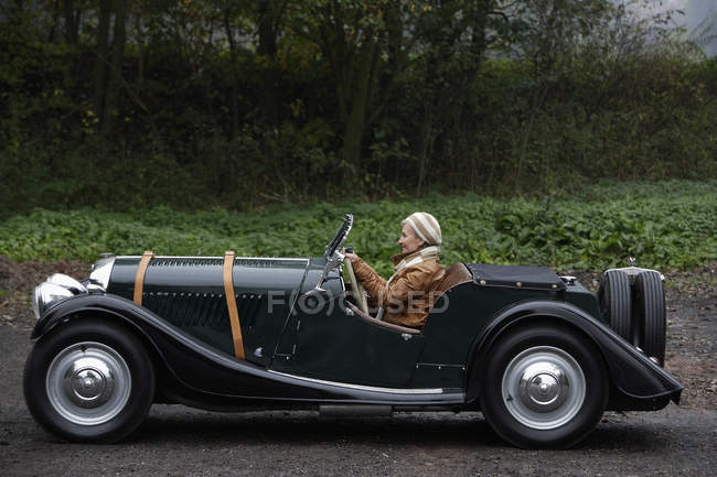 Senior femme conduite voiture antique — Photo de stock