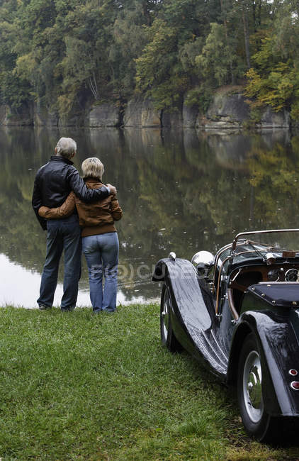 Senior couple standing next to pond — Stock Photo