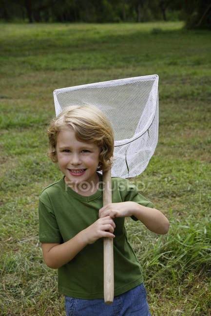 Мальчик держит в руках сетку для бабочек — стоковое фото