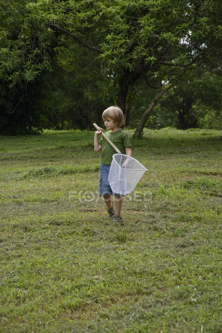 Мальчик держит в руках сетку для бабочек — стоковое фото