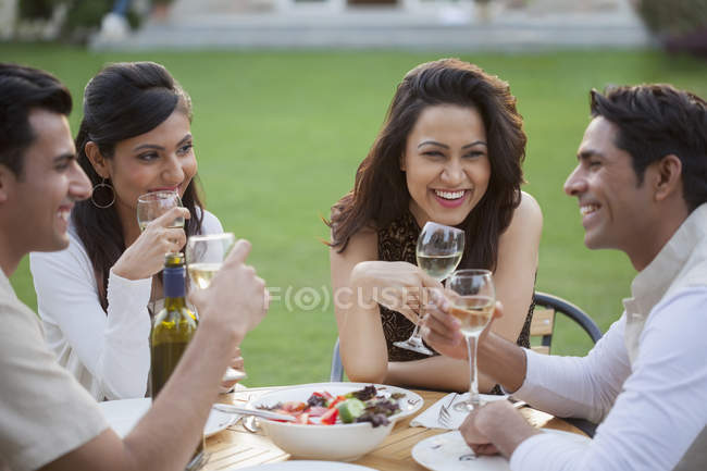 Друзі п'ють вино за столом — стокове фото