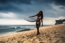 Mulher de fato de mergulho carregando prancha na praia — Fotografia de Stock