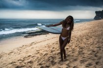 Жінка, що носить дошку для серфінгу на пляжі — стокове фото