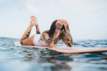 Женщина лежит на доске для серфинга — стоковое фото