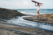 Woman walking with surf board — Stock Photo