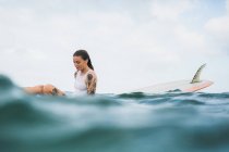Frau sitzt auf Surfbrett — Stockfoto