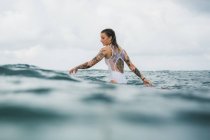 Mujer sentada en tabla de surf - foto de stock