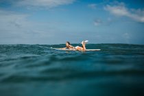Mulher que coloca na prancha de surf no mar — Fotografia de Stock