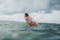 Женщина сидит на доске для серфинга — стоковое фото