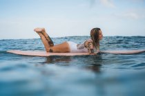 Mujer acostada sobre tabla de surf - foto de stock