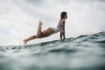 Жінка стоїть в позі на дошці для серфінгу — стокове фото