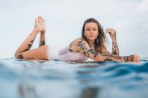 Mulher que coloca no surf board — Fotografia de Stock