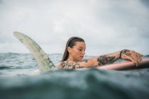 Woman holding surf board in water — Stock Photo