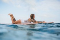 Femme posée sur planche de surf — Photo de stock