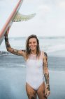 Жінка тримає дошку для серфінгу на пляжі — стокове фото