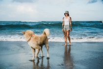 Жінка гуляє з собакою на пляжі — стокове фото
