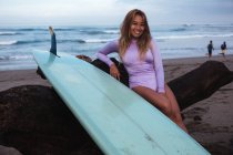 Surfista sentado com prancha de surf na praia — Fotografia de Stock