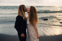 Vista laterale di giovani coppie che si baciano sulla spiaggia di sabbia — Foto stock