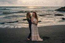 Вид спереду чоловіка, що обіймає жінку на піщаному пляжі — стокове фото