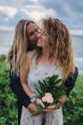 Vista frontal do jovem abraçando mulher segurando flores — Fotografia de Stock