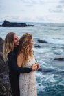 Side view of young couple gently hugging on seaside and looking away — Stock Photo