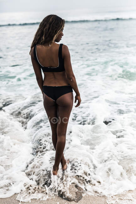 Giovane donna in piedi sulla spiaggia — Foto stock