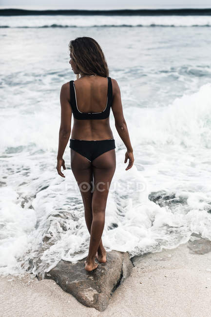 Giovane donna in piedi sulla spiaggia — Foto stock