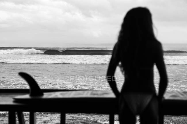 Mujer joven en traje de neopreno y con tabla de surf - foto de stock