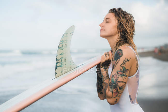 Woman holding surf board on beach — Stock Photo