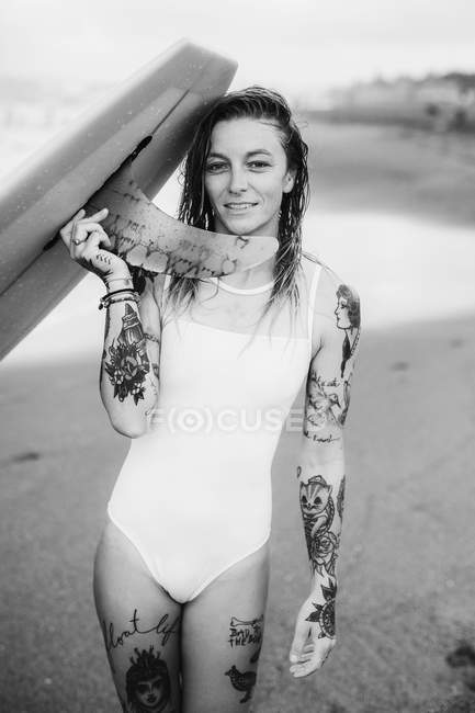 Жінка тримає дошку для серфінгу на пляжі — стокове фото