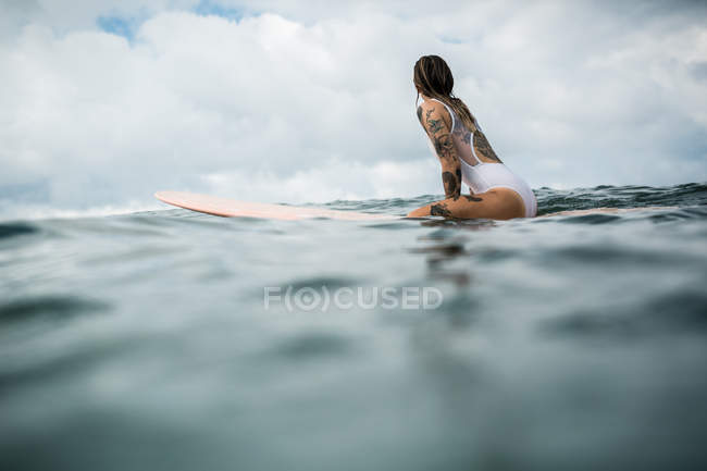 Жінка сидить на дошці для серфінгу — стокове фото