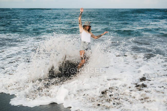 Mulher em onda respingo na praia — Fotografia de Stock