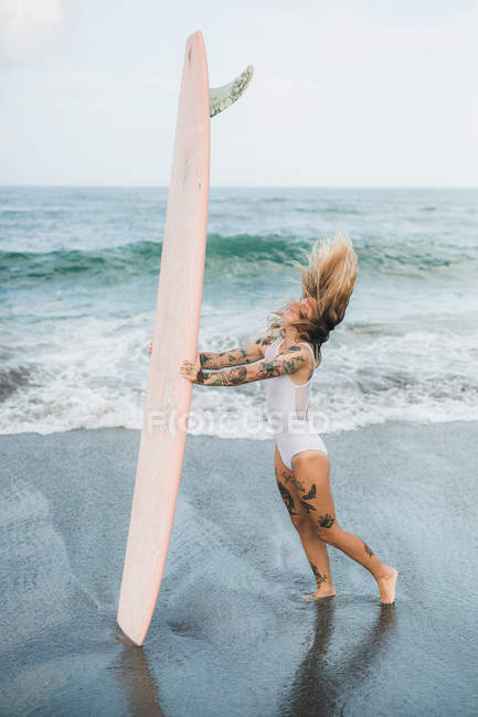 Femme tenant planche de surf sur la plage — Photo de stock