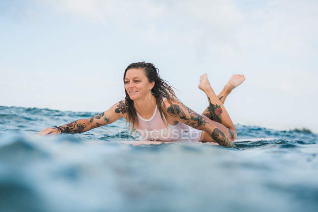 Donna sdraiata su tavola da surf — Foto stock