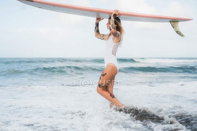 Woman holding surf board on beach — Stock Photo