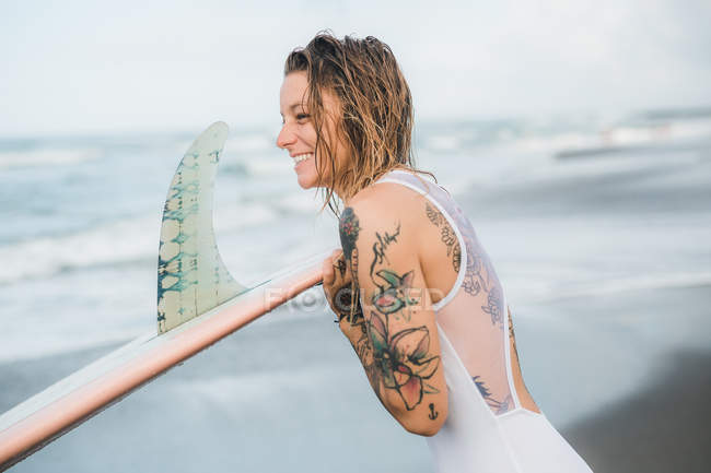 Mulher segurando prancha de surf na praia — Fotografia de Stock
