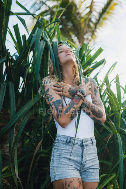Woman in green bushes with crossed arms — Stock Photo