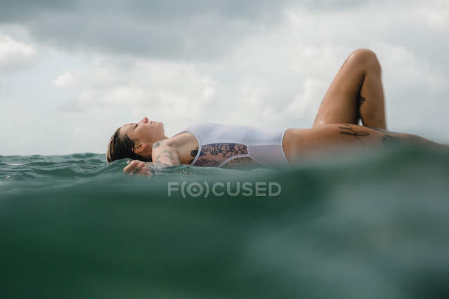 Mulher que coloca no surf board — Fotografia de Stock
