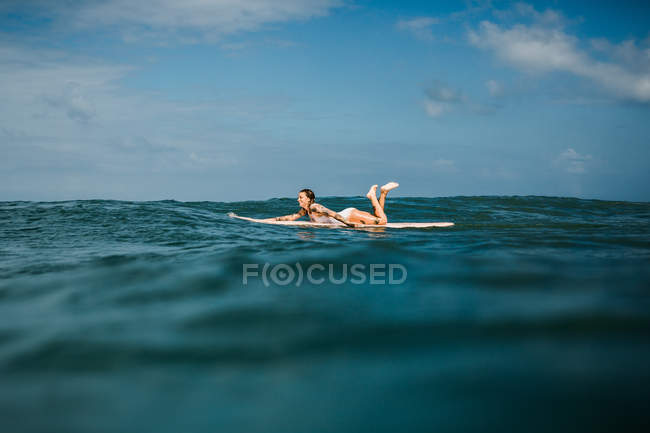 Mulher que coloca na prancha de surf no mar — Fotografia de Stock