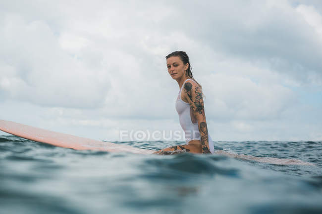 Женщина сидит на доске для серфинга — стоковое фото