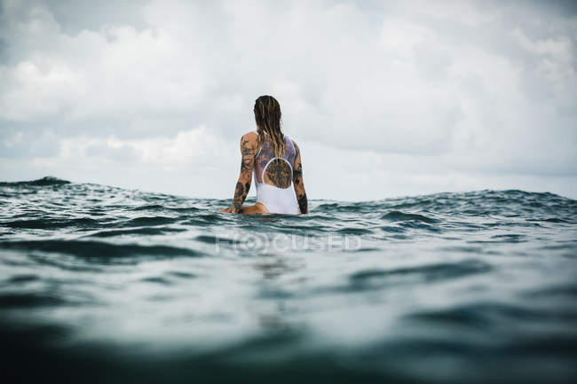 Femme assise sur une planche de surf — Photo de stock