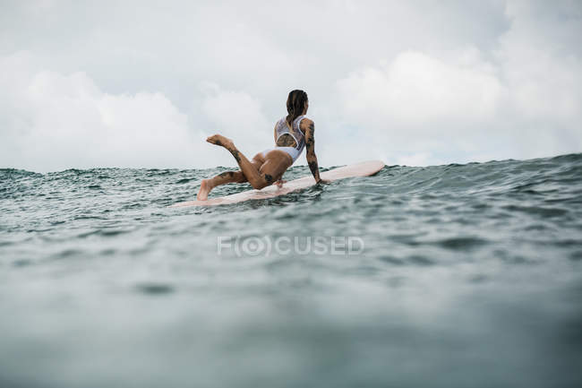 Женщина стоит в позе на доске для серфинга — стоковое фото