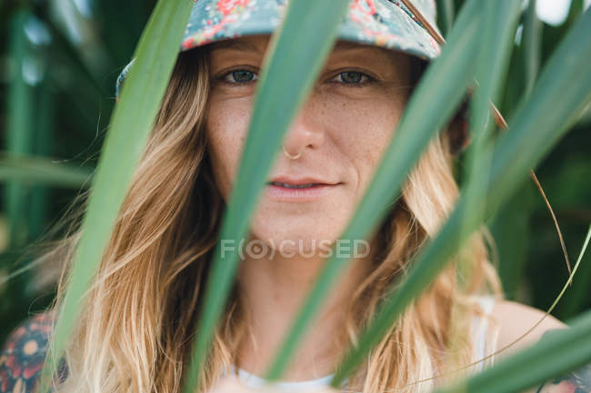 Frau im grünen Gebüsch blickt in Kamera — Stockfoto