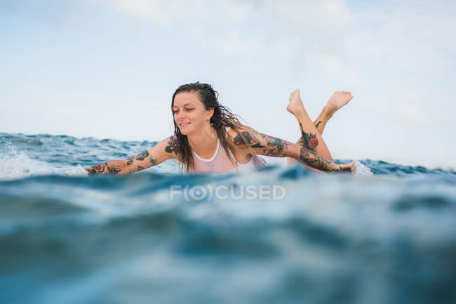 Женщина лежит на доске для серфинга — стоковое фото