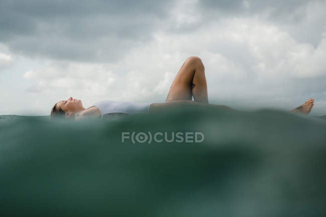 Mujer acostada sobre tabla de surf - foto de stock